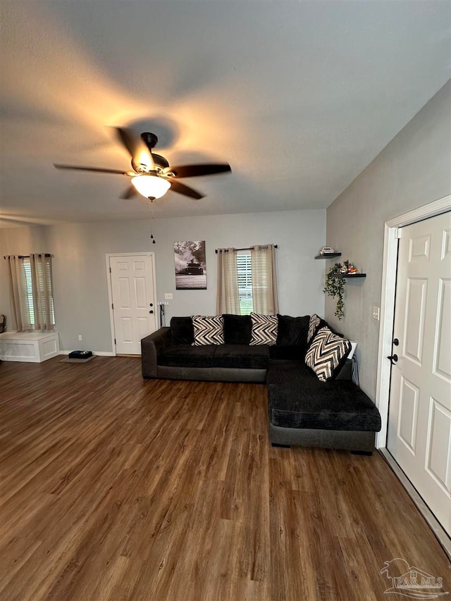 living room featuring ceiling fan and dark wood-type flooring