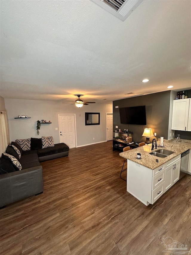 kitchen with ceiling fan, white cabinets, stainless steel dishwasher, dark wood-type flooring, and a breakfast bar area