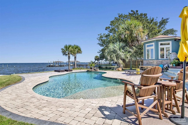 view of pool with a patio, a water view, and an outdoor structure