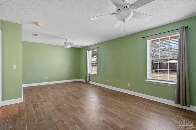 unfurnished room with ceiling fan, a textured ceiling, a wealth of natural light, and wood-type flooring