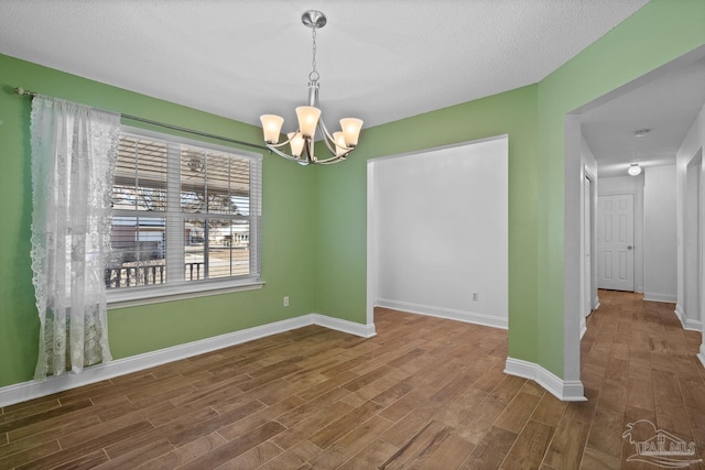 spare room featuring dark wood-type flooring, a textured ceiling, and a chandelier