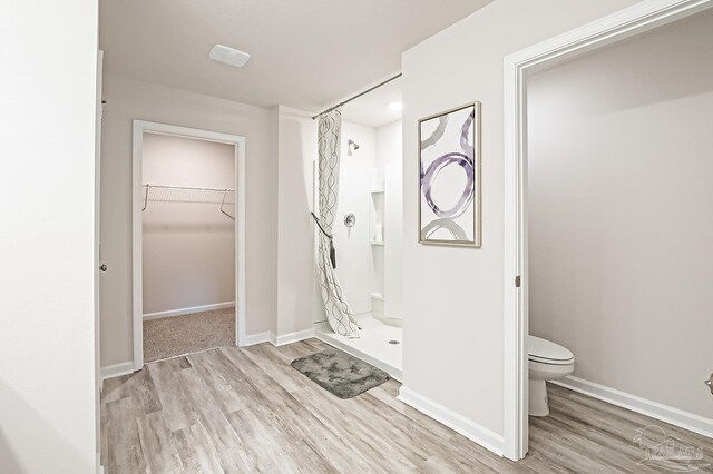8815 Longmont Way, Milton, FL 32583 - full bathroom with a stall shower, baseboards, toilet, and wood finished floors
