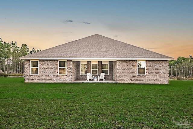 8815 Longmont Way, Milton, FL 32583 - back of house at dusk with a patio area, brick siding, and a lawn
