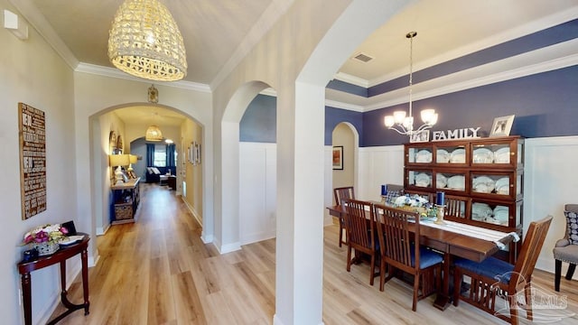 dining room with light wood-type flooring, an inviting chandelier, and ornamental molding