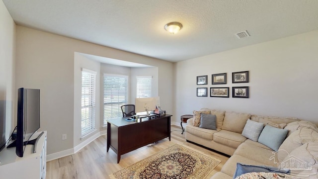 office with light hardwood / wood-style flooring and a textured ceiling