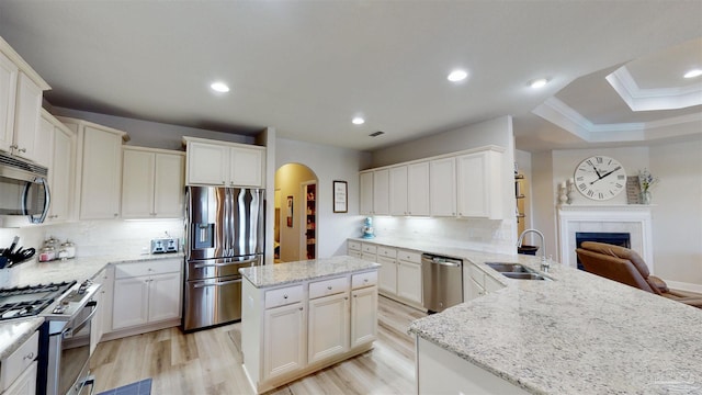 kitchen featuring sink, stainless steel appliances, tasteful backsplash, kitchen peninsula, and a fireplace