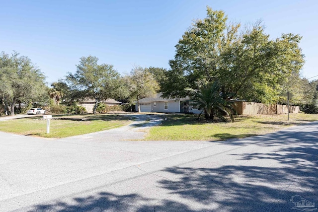 view of front facade featuring driveway, a front lawn, an attached garage, and fence