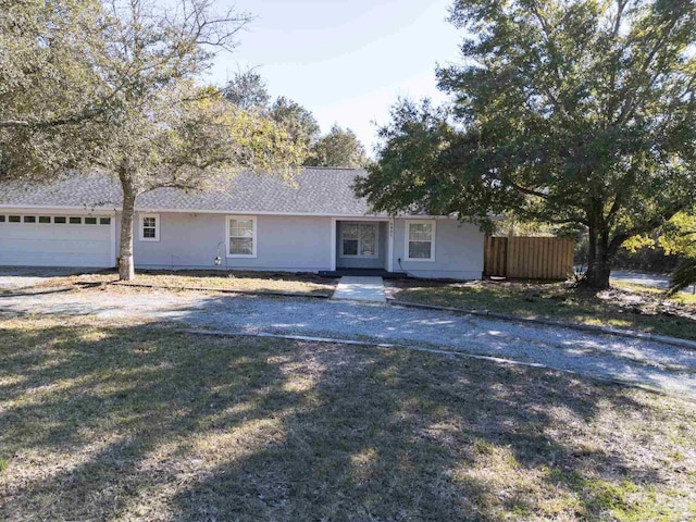 ranch-style home with a garage, fence, driveway, and a front lawn