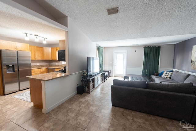 kitchen with visible vents, open floor plan, a textured ceiling, stainless steel fridge, and a peninsula