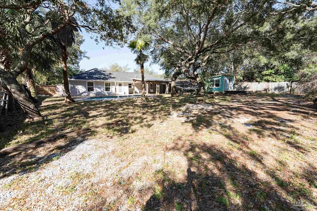 view of yard featuring a storage unit, an outdoor structure, a fenced backyard, and a fenced in pool