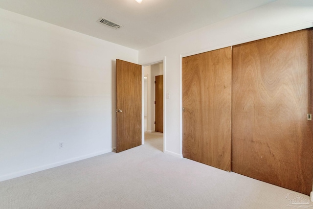 unfurnished bedroom featuring light carpet and a closet