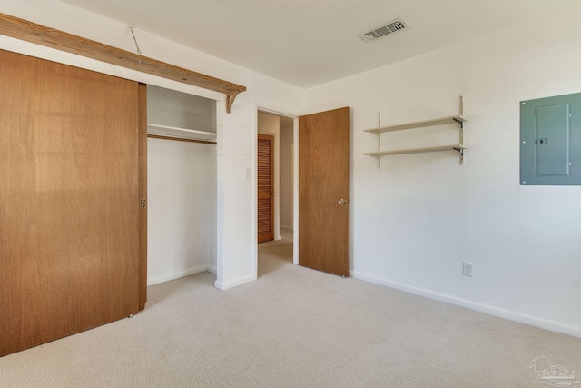 unfurnished bedroom with a closet, electric panel, and light colored carpet