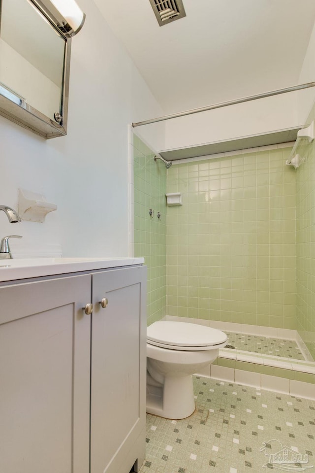 bathroom featuring tile patterned floors, toilet, tiled shower, and vanity