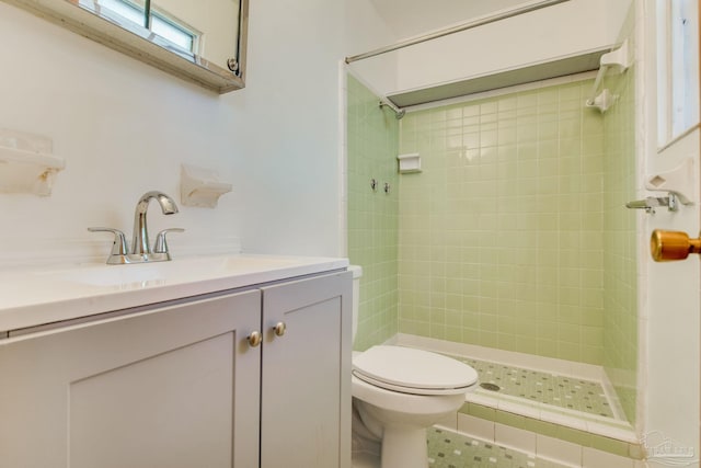 bathroom featuring toilet, vanity, tile patterned flooring, and tiled shower