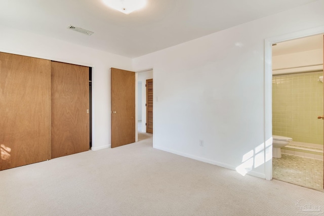 unfurnished bedroom featuring carpet floors, a closet, and ensuite bath