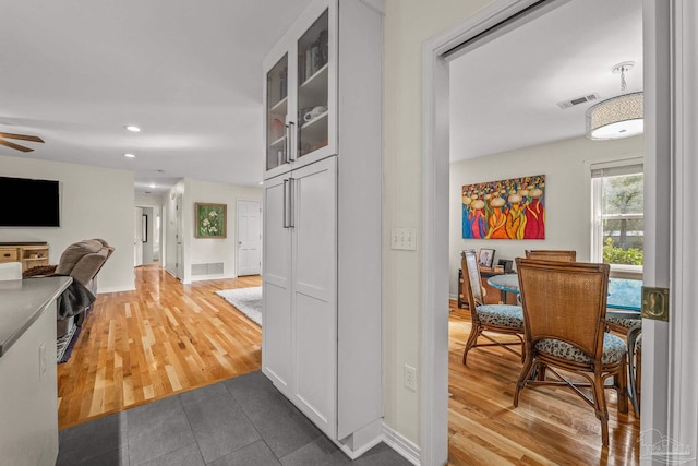 interior space featuring white cabinetry, wood-type flooring, and ceiling fan