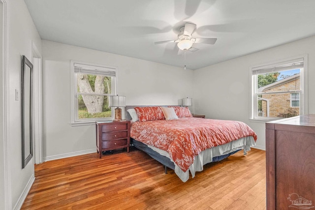 bedroom featuring ceiling fan, hardwood / wood-style floors, and multiple windows