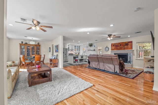 living room featuring hardwood / wood-style floors, a fireplace, and ceiling fan