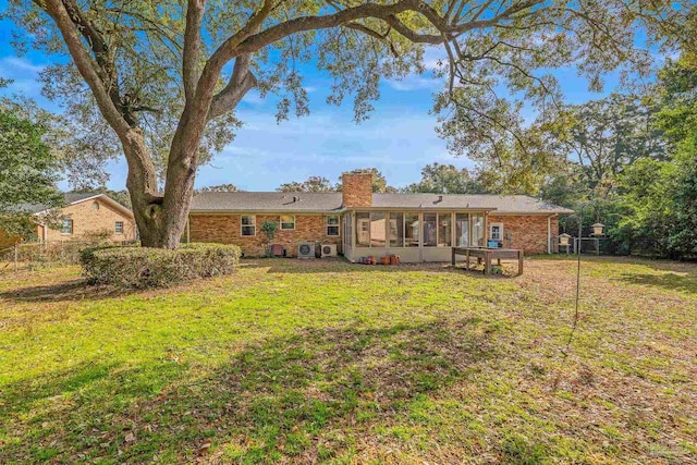 back of house featuring a sunroom and a lawn