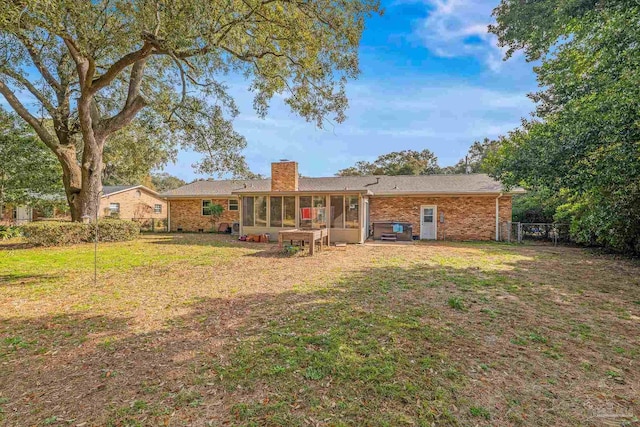 rear view of house featuring a yard and a sunroom