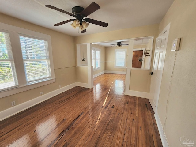 empty room featuring a healthy amount of sunlight, wood-type flooring, and baseboards