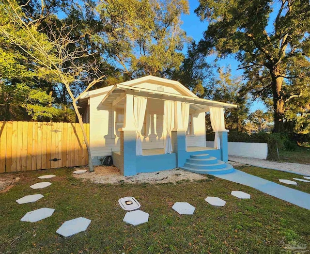 bungalow featuring an outbuilding, fence, and a front lawn