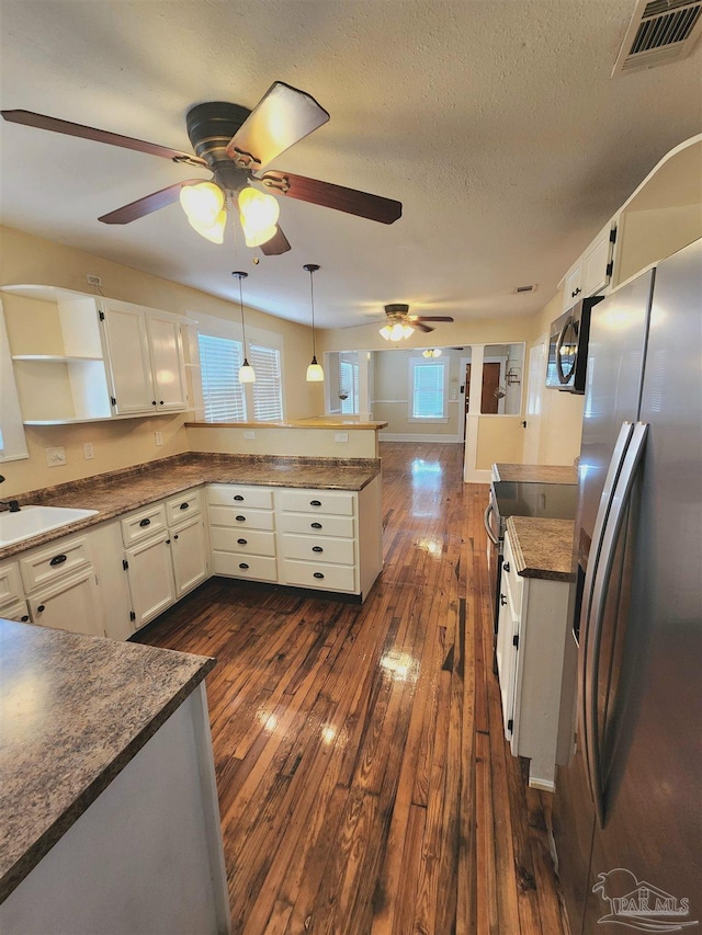 kitchen with open shelves, visible vents, freestanding refrigerator, a sink, and a peninsula