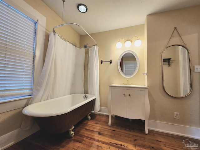 full bathroom with a freestanding tub, hardwood / wood-style flooring, vanity, baseboards, and a shower with curtain