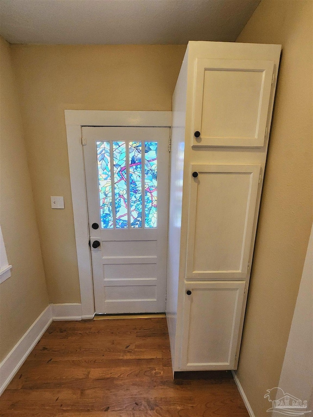 doorway to outside with dark wood-type flooring and baseboards