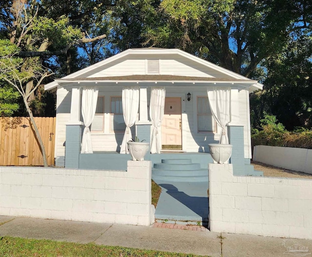 bungalow with french doors, a porch, and a fenced front yard