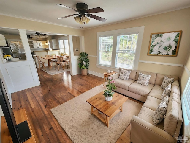 living area with ceiling fan, baseboards, crown molding, and wood finished floors