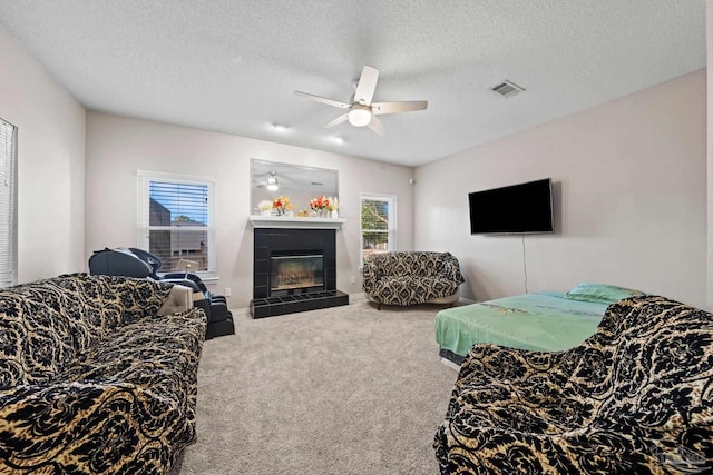 living room featuring ceiling fan, a textured ceiling, a fireplace, and carpet floors