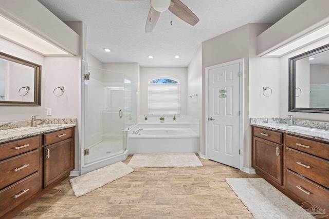 bathroom featuring a textured ceiling, ceiling fan, vanity, and separate shower and tub