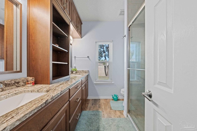 bathroom featuring vanity, a textured ceiling, hardwood / wood-style flooring, walk in shower, and toilet