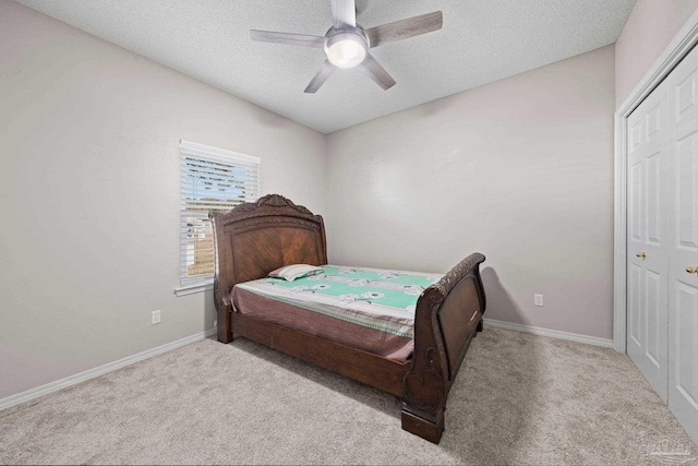 carpeted bedroom with a textured ceiling, ceiling fan, and a closet