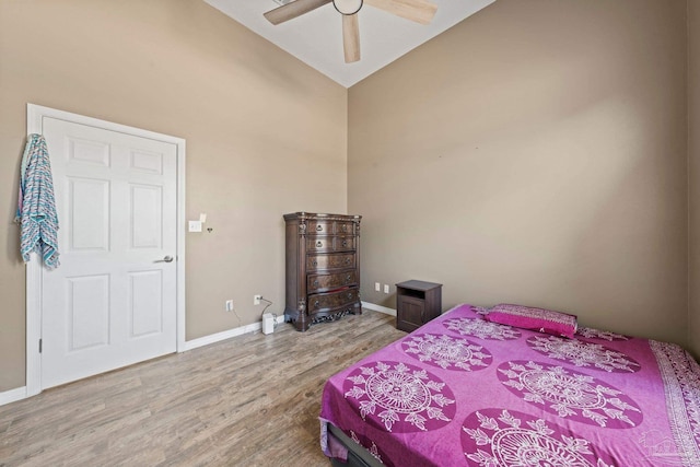 bedroom featuring light hardwood / wood-style flooring, ceiling fan, and high vaulted ceiling