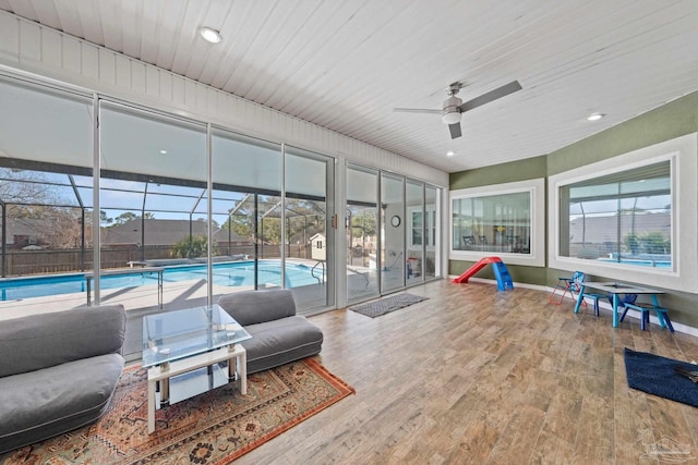 sunroom featuring ceiling fan, a swimming pool, and wooden ceiling