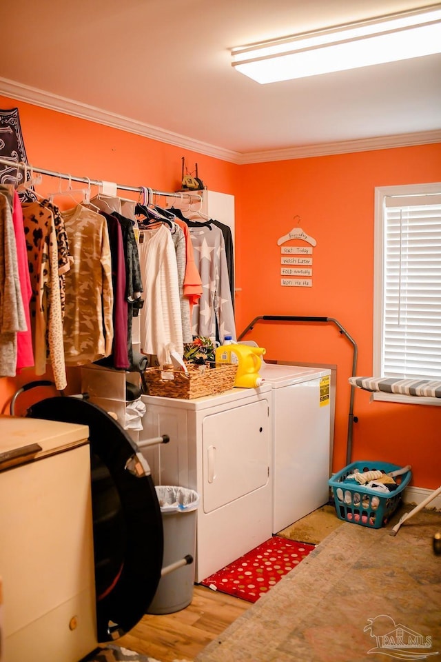 washroom featuring washing machine and clothes dryer, ornamental molding, and light hardwood / wood-style flooring