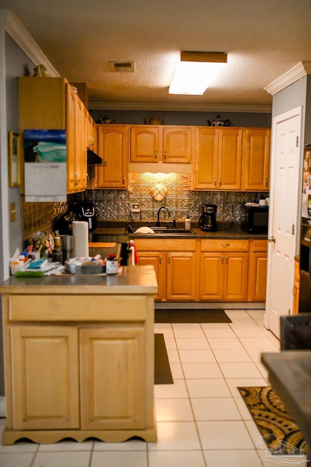 kitchen featuring tasteful backsplash, ornamental molding, a textured ceiling, and light tile patterned floors