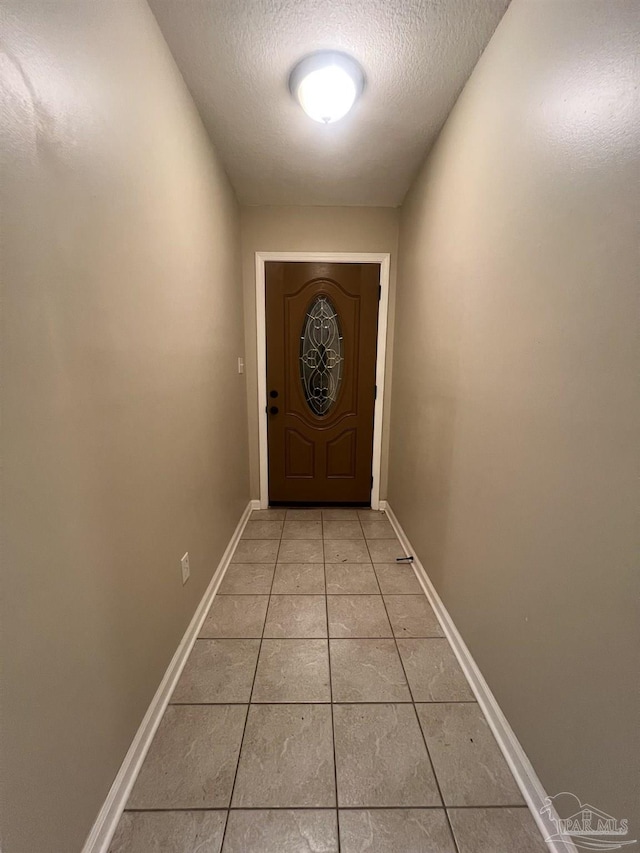 doorway with light tile patterned floors and a textured ceiling