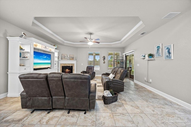 3920 Shady Grove Dr, Pace, FL 32571 - living area with a tray ceiling, a ceiling fan, baseboards, a lit fireplace, and crown molding