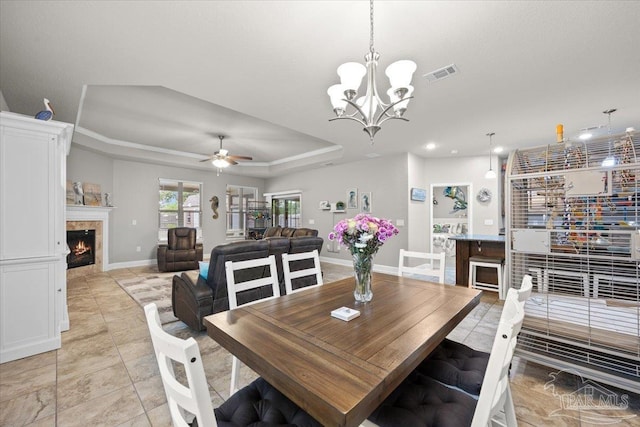 3920 Shady Grove Dr, Pace, FL 32571 - dining room featuring a raised ceiling, a tile fireplace, light tile patterned flooring, baseboards, and a chandelier