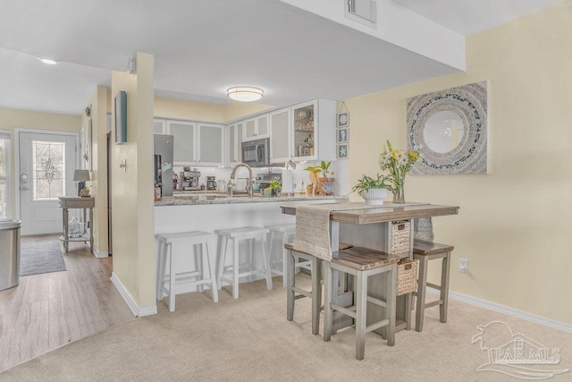 10443 Gulf Beach Hwy Unit 1, Pensacola, FL 32507 - kitchen featuring a kitchen breakfast bar, white cabinets, light stone countertops, appliances with stainless steel finishes, and glass insert cabinets
