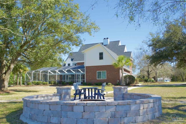 back of house featuring glass enclosure, brick siding, a lawn, and a chimney