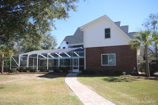 rear view of house featuring glass enclosure, brick siding, a yard, and roof with shingles