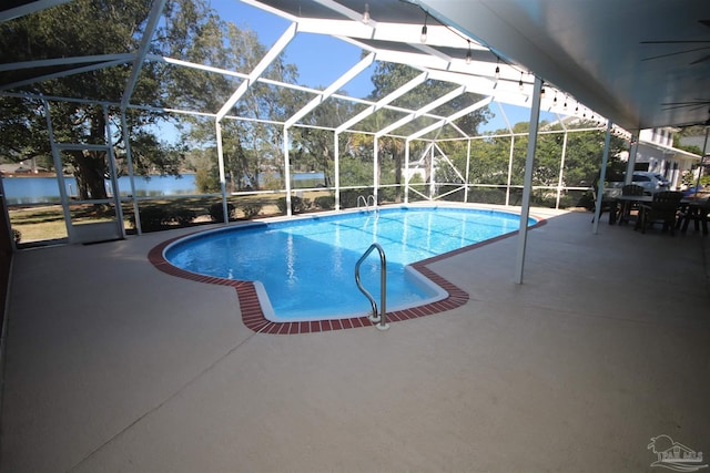 outdoor pool featuring glass enclosure, a patio, and a water view