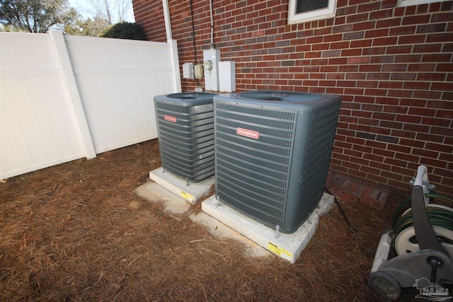 exterior details with central air condition unit, fence, and brick siding