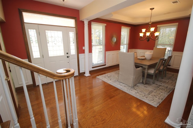 dining space with a wealth of natural light, an inviting chandelier, ornate columns, and wood finished floors