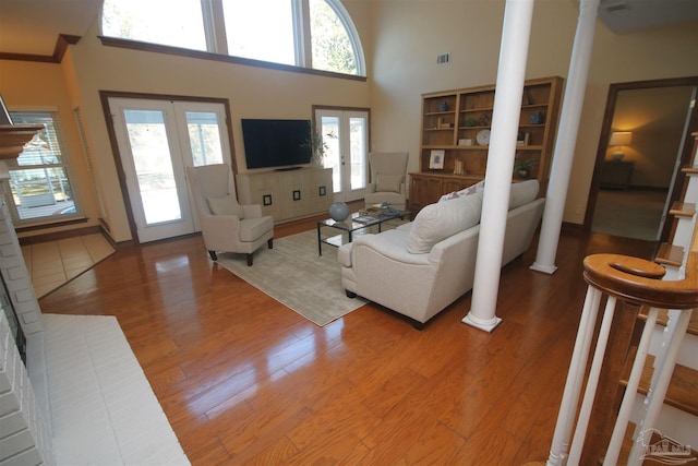 living area featuring french doors, wood finished floors, visible vents, and ornate columns