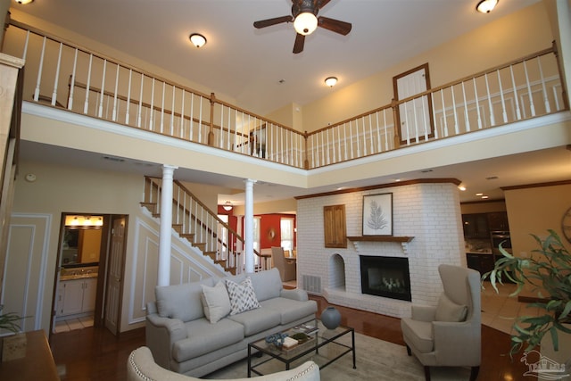 living area with stairway, wood finished floors, visible vents, and ornate columns